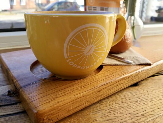 Gelbe Kaffeetasse mit Loppokaffee-Logo